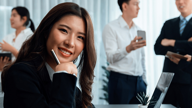 Focus portrait of female manger, businesswoman in the harmony meeting room with blurred of colleagues working together, analyzing financial paper report and dashboard data in background.