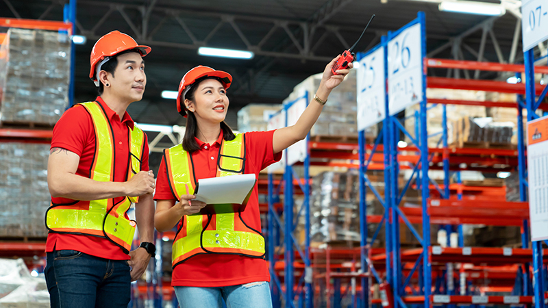 Workers and manager discussing completed work in a large warehouse